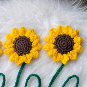 Peut inclure: Trois marque-pages en crochet en forme de tournesol avec des tiges et des feuilles vertes. Les tournesols ont des centres bruns et des pétales jaunes.