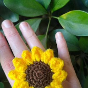 Peut inclure: Une bague en forme de tournesol crocheté avec des pétales jaunes et un centre brun.