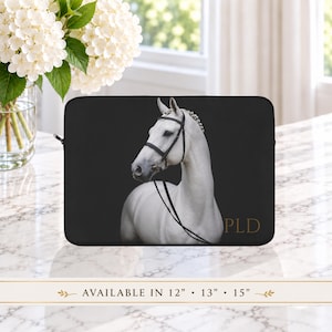 May include: A black laptop sleeve featuring a white horse wearing a black bridle against a dark background. The letters PLD are printed in gold on the bottom right. Text at the bottom indicates the sleeve is available in 12, 13, and 15 inches.