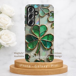 May include: A phone case featuring a stained glass pattern of green shamrocks with gold outlines and an iridescent background. The name Shannon is printed in white script across the center. The case has a vertical camera cutout on the left side.