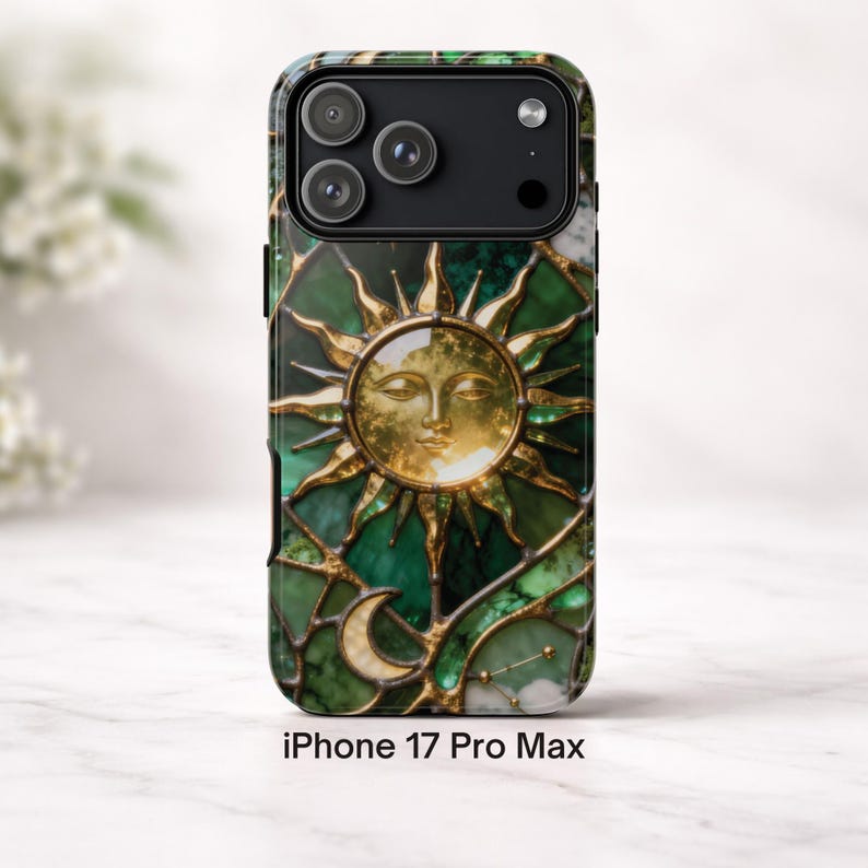 K&ouml;nnte beinhalten: Handyh&uuml;lle mit einem Buntglasdesign mit goldener Sonne, Mond und Sternen auf gr&uuml;nem und goldenem Hintergrund. Die H&uuml;lle ist mit "iPhone 17 Pro Max" beschriftet.