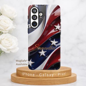 May include: A phone case with a patriotic design featuring red, white, and blue stripes and white stars. The name "Samantha" is written in gold script. The case is displayed on a wooden stand. The text "MagSafe Available" is visible.