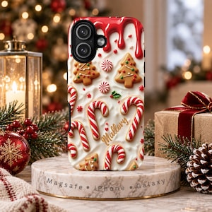 May include: A phone case featuring a white background with red icing drips at the top, decorated with gingerbread trees, red and white candy canes, and peppermint swirls. The name Mallory is written in gold script. The base is labeled Magsafe iPhone Galaxy.