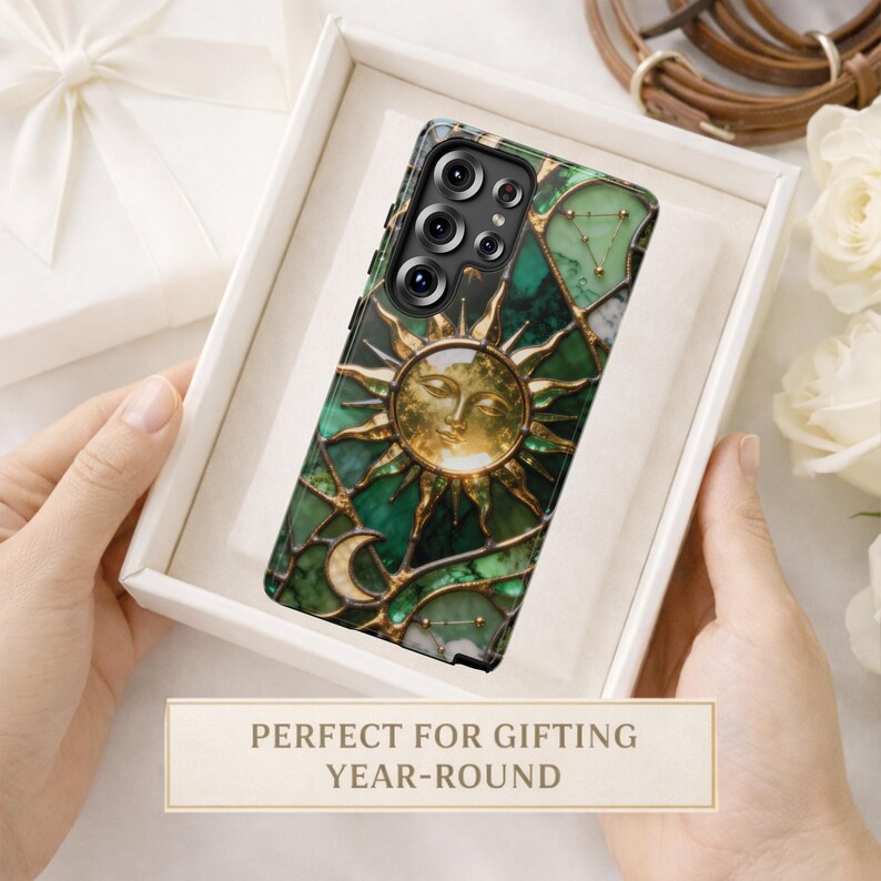 K&ouml;nnte beinhalten: Dekorative Handyh&uuml;lle mit Sonnen- und Monddesign mit gr&uuml;nen und goldenen Akzenten. Die H&uuml;lle wird in einer wei&szlig;en Geschenkbox pr&auml;sentiert. Der Text auf dem Bild lautet: PERFEKT ZUM VERSCHENKEN GANZJ&Auml;HRIG.