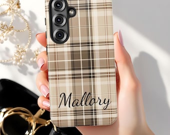 May include: A phone case with a plaid pattern in shades of brown and beige. The name "Mallory" is written in a cursive font across the bottom. The case has a camera module with three lenses.