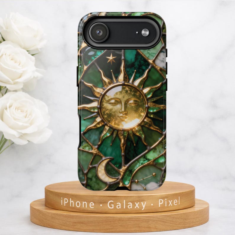 Green emerald stained glass phone case featuring a gold sun with sculpted rays centered on the design, surrounded by crescent moon and star details. The case displays rich green marble textures with metallic gold lead lines, creating a luminous celestial pattern. Shown as a MagSafe-compatible protective phone case for iPhone, Samsung, and Google Pixel, photographed against a clean white background with a polished finish.