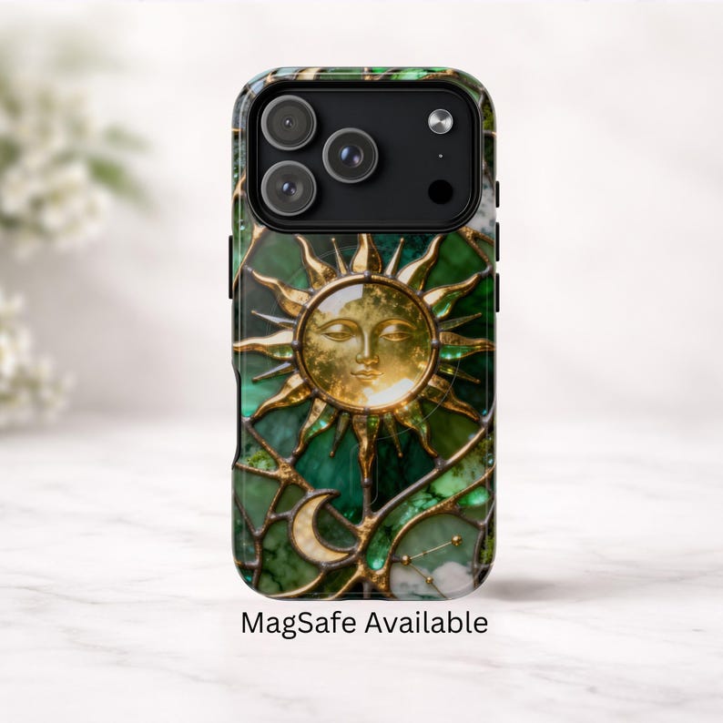 K&ouml;nnte beinhalten: Handyh&uuml;lle mit einem Buntglasdesign. Sie zeigt eine goldene Sonne, einen Mond und Sterne auf gr&uuml;nem Hintergrund. Das Geh&auml;use hat ein schwarzes Kameramodul und den Text "MagSafe Available".