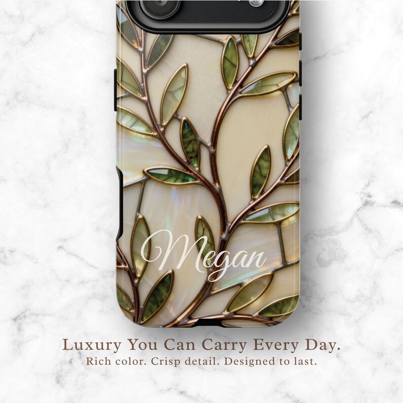 May include: A phone case featuring a stained glass-inspired pattern of copper-toned branches and green leaves against a cream-colored background. The name Megan is written in white cursive script across the center of the design.