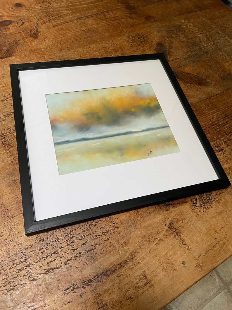 May include: A framed painting of a landscape with a yellow and orange sky reflected in a body of water. The painting is in a black frame.