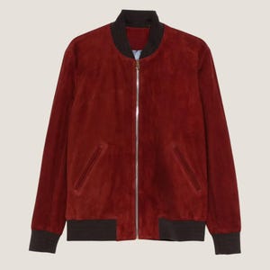 May include: A red suede bomber jacket with a black collar, cuffs, and hem. The jacket has a silver zipper and two front pockets. This outerwear is a classic style.