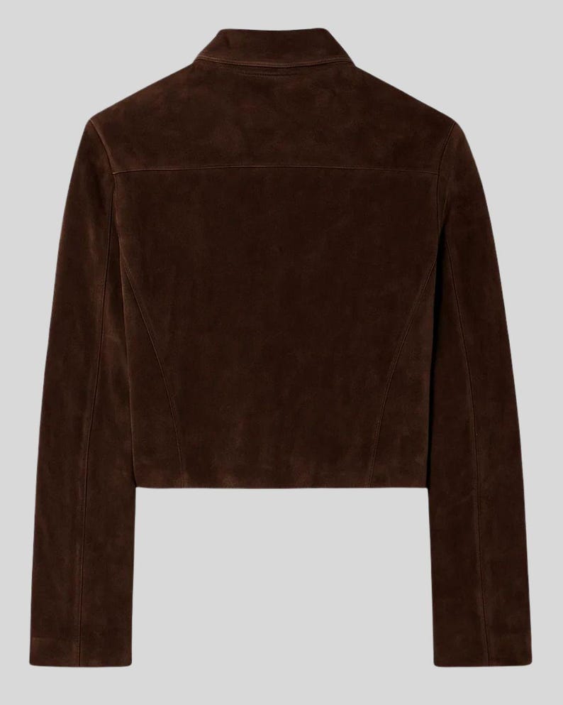 May include: A cropped brown suede jacket with a classic collar and long sleeves. The back view of the jacket shows a tailored fit with a yoke detail. The jacket is a solid colour and has a smooth texture.