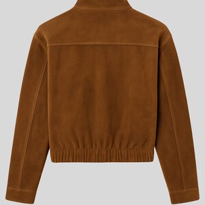 May include: A brown suede jacket with a high collar and a ribbed hem. The jacket has a zipper closure and a simple, classic design. The back of the jacket features a horizontal seam across the upper back.