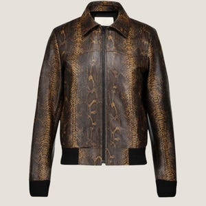 Pode incluir: Casaco de couro castanho e bege com padrão de pele de cobra, com fecho de correr preto e punhos e bainha canelados pretos. O casaco tem gola e uma silhueta clássica de casaco bomber.