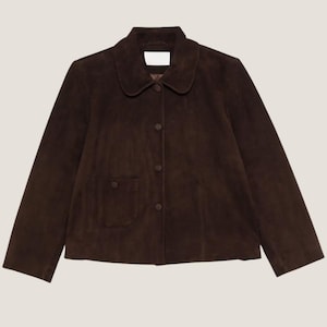 Op de afbeelding: Een donkerbruine suède jas met een ronde kraag en een knoopsluiting. De jas heeft twee voorzakken en lange mouwen. Het kledingstuk is een klassieke stijl, geschikt voor diverse gelegenheden.