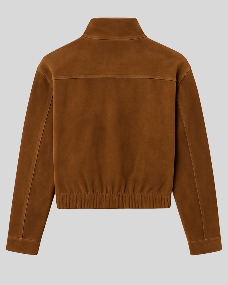 May include: A brown suede jacket with a high collar and a ribbed hem. The jacket has a zipper closure and a horizontal seam across the upper back. The sleeves are long and end in a buttoned cuff.