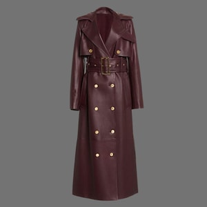 Peut inclure: Un long manteau en cuir bordeaux à double boutonnage et ceinture. Le manteau a des boutons dorés et un style classique de trench-coat.
