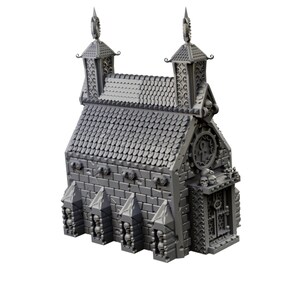 Op de afbeelding: Een grijs 3D-geprint model van een gotisch gebouw met een bakstenen gevel, een dak van shingles en een schedelvormige deur. Het gebouw heeft twee torens met puntige daken en decoratieve details.
