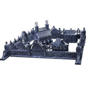 Op de afbeelding: Een grijze 3D-geprinte miniatuurset van een gotische begraafplaats met een kerk, een klein huis en een hek. De set is ontworpen voor tabletop-gaming.