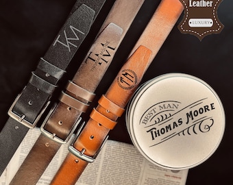 May include: Three leather belts in black, brown, and tan, each with a silver buckle. The belts are embossed with initials and the brand name "Thomas Moore." A round tin with "Best Man Thomas Moore" is also visible.