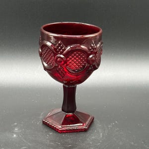 May include: A white ceramic mug with a black handle and the text "But First, Coffee" in a handwritten style. The mug is on a white surface. The mug is likely for hot beverages.