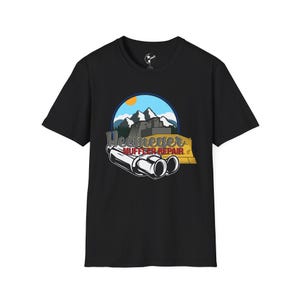 Könnte beinhalten: Schwarzes T-Shirt mit einem Aufdruck von "Heemeyer Muffler Repair". Das Design zeigt eine Berglandschaft, einen Schalldämpfer und einen Goldbarren. Das T-Shirt hat einen Rundhalsausschnitt.