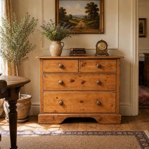 May include: A light brown wooden chest of drawers featuring two small top drawers and two full-width bottom drawers, each equipped with simple round wooden knobs. The piece has a rectangular top surface and a base with a curved cutout detail.