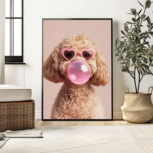 May include: A light brown poodle dog wearing pink heart-shaped sunglasses and blowing a pink bubble. The dog is looking directly at the camera. The background is a light pink color.