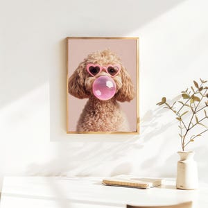 May include: A light brown poodle wearing pink heart-shaped sunglasses and blowing a pink bubble. The dog is looking directly at the camera. The background is a light pink color.