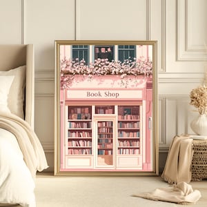 May include: A framed print depicting a pink book shop with the text "Book Shop" above the entrance. The shop's windows are filled with books and the top is decorated with pink flowers. The print is in a gold frame.