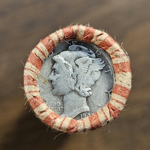 Könnte beinhalten: Eine silberne Mercury Dime-Münze aus dem Jahr 1945 in einer roten und weißen Papier-Münzverpackung.