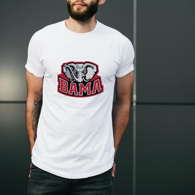 Pu&ograve; includere: T-shirt bianca con grafica di una testa di elefante e la scritta "BAMA" in rosso e bianco. La maglietta &egrave; realizzata in materiale morbido, adatta per un abbigliamento casual. Il design &egrave; un logo di una squadra sportiva.
