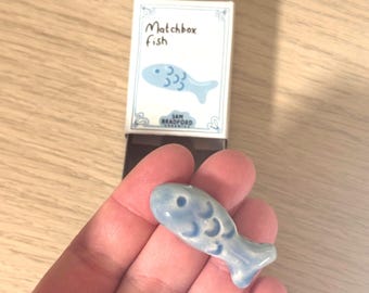 Pez de cerámica hecho a mano en una caja de cerillas dibujada a mano: un juguete artístico en miniatura para regalar.