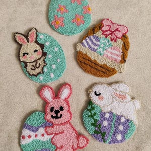 May include: Five handmade felt Easter decorations featuring bunnies and eggs. The decorations are made with colorful yarn and are perfect for adding a touch of spring to your home.