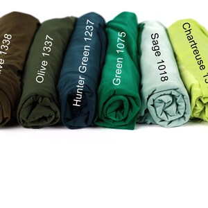a collection of six rolled-up shirts in various colors, including olive green, hunter green, green, sage, and chartreuse.