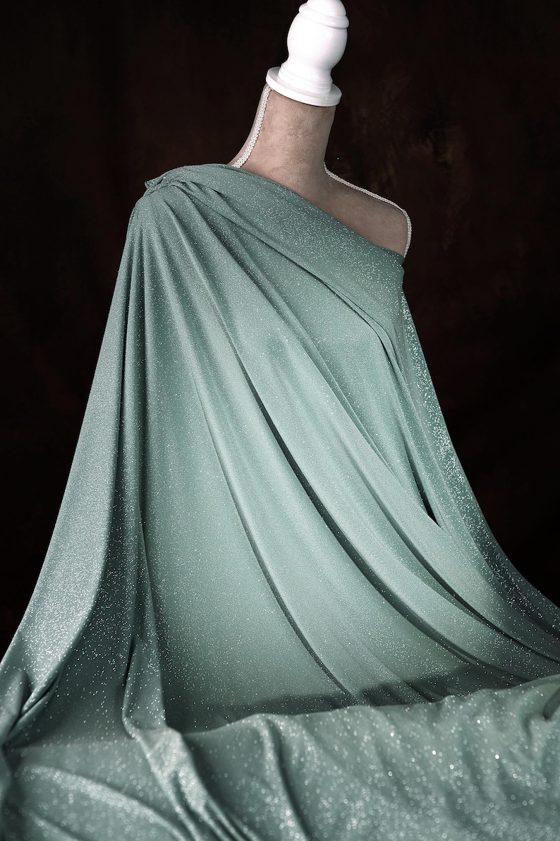 A mannequin wearing a flowing, mint green fabric draped over its body, creating a draped and flowing silhouette.