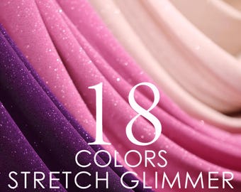 May include: A collection of stretch glimmer knit fabric in various shades of purple, pink, and beige, arranged in soft, flowing folds. The text 18 COLORS STRETCH GLIMMER KNIT FABRIC is centered over the fabric, featuring a subtle sparkling texture.