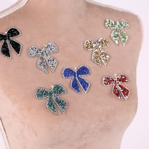 A mannequin bust with various colorful, sparkling rhinestone or crystal-like embellishments attached to it, including multiple bows and butterflies.