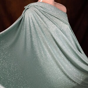 A flowing, shimmering green dress with a sparkly texture, creating a sense of movement and elegance.