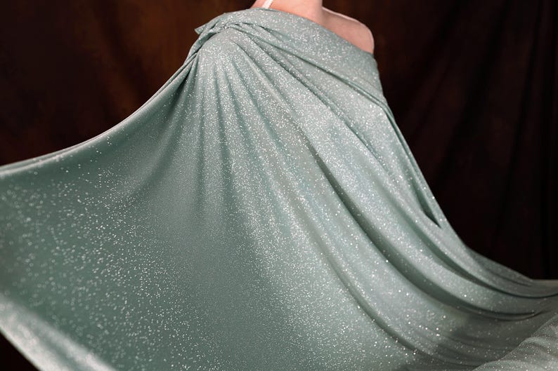 A flowing, shimmering green dress with a sparkly texture, creating a sense of movement and elegance.