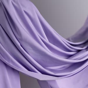 A hand is holding a piece of lavender fabric, which appears to be a soft, flowing material.