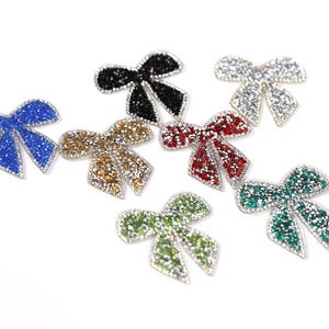 six colorful, glittery bows in various colors and sizes, arranged on a white background.
