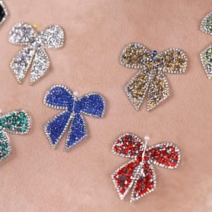 a close-up view of a person's arm adorned with a variety of colorful, sparkling rhinestone-encrusted bows.