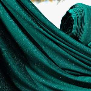 A close-up view of a shiny, glittery fabric in a dark green color.