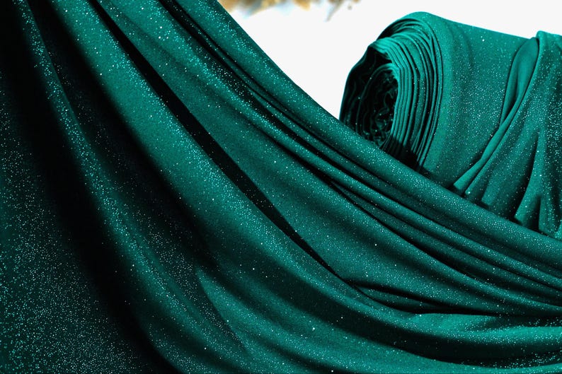 A close-up view of a shiny, glittery fabric in a dark green color.