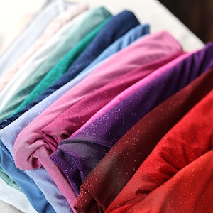 a bunch of different colors of cloth on a bed