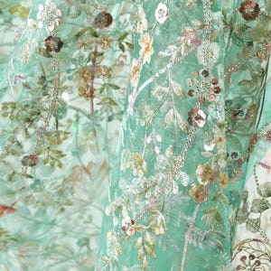 The image is a close-up view of a fabric with a floral pattern, featuring various shades of green, pink, and white flowers and leaves.