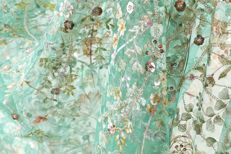 The image is a close-up view of a fabric with a floral pattern, featuring various shades of green, pink, and white flowers and leaves.