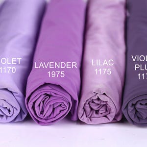 Four rolled-up fabric swatches in different shades of purple, labeled with the names of the colors: violet, lavender, lilac, and plum.