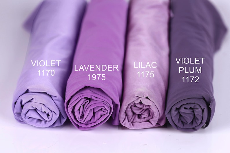 Four rolled-up fabric swatches in different shades of purple, labeled with the names of the colors: violet, lavender, lilac, and plum.