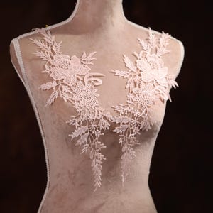 Könnte beinhalten: Eine zarte rosa Spitzenapplikation mit Blumenmustern, perfekt um Kleidung oder Bastelarbeiten einen Hauch von Eleganz zu verleihen.